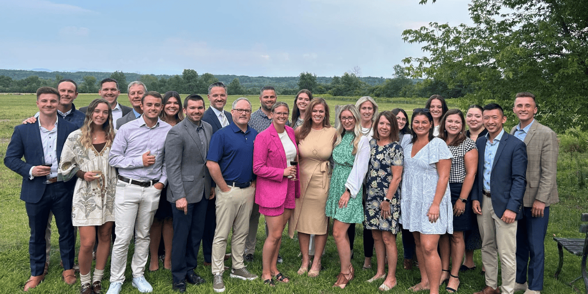 coworkers posing in front of a field with wine at a corporate mixer