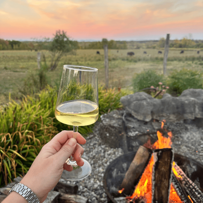 Guest enjoying time by the fire pit with a glass of wine at Galway Rock Winery near Saratoga Springs